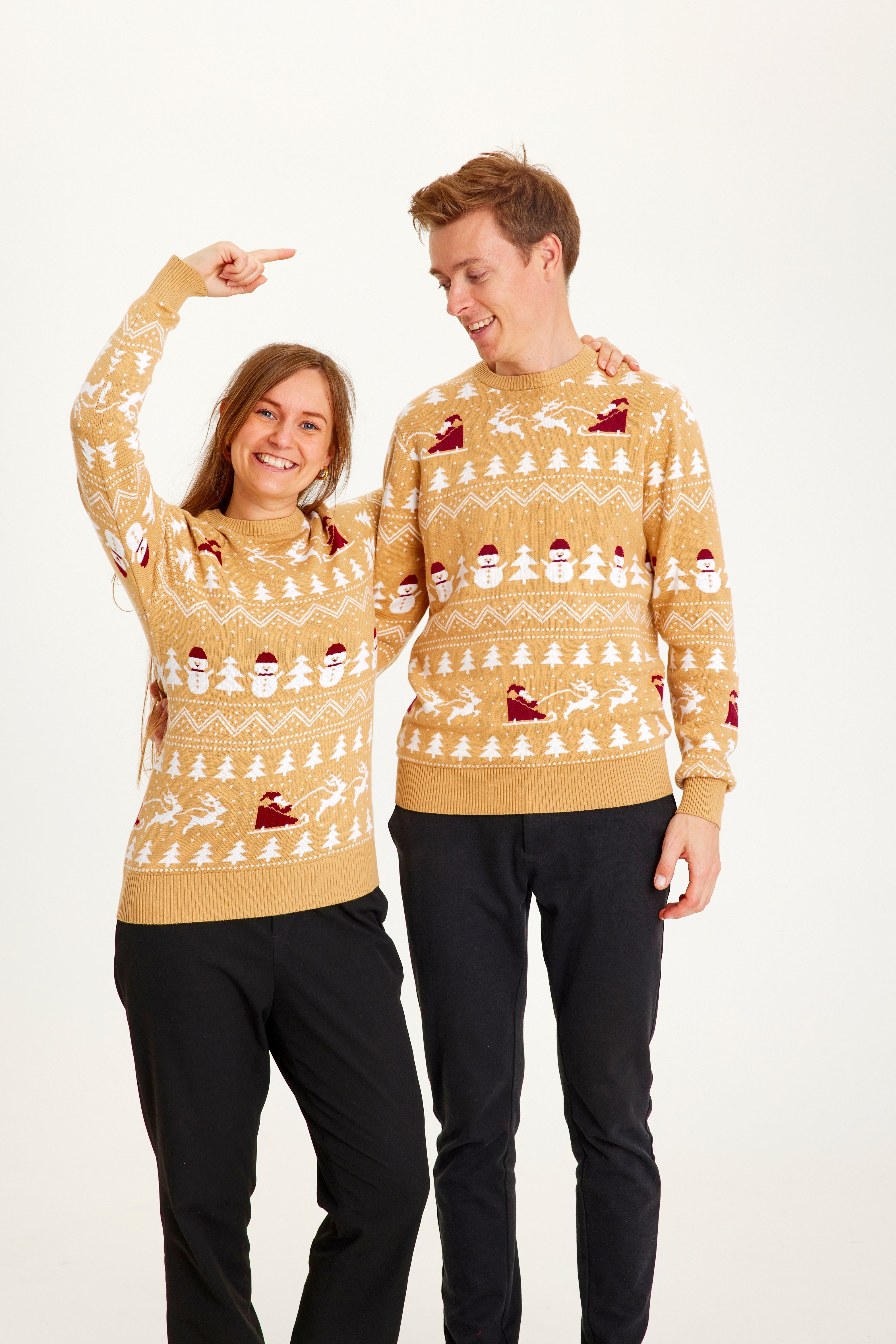 Ein Paar trägt einen beigen Weihnachtspulli mit einem Muster darauf.